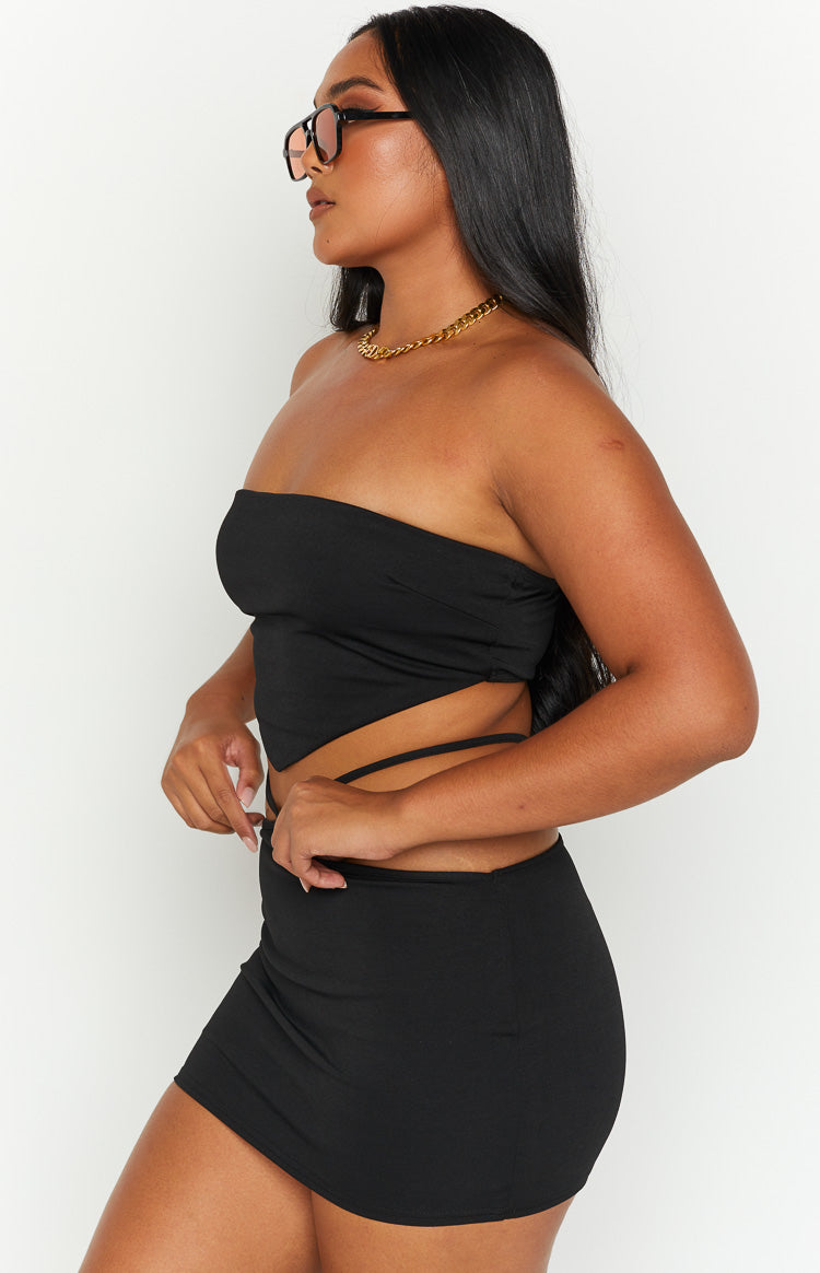 Side view of a black strapless bandana top with a pointed hem and thin tie straps wrapping around the waist