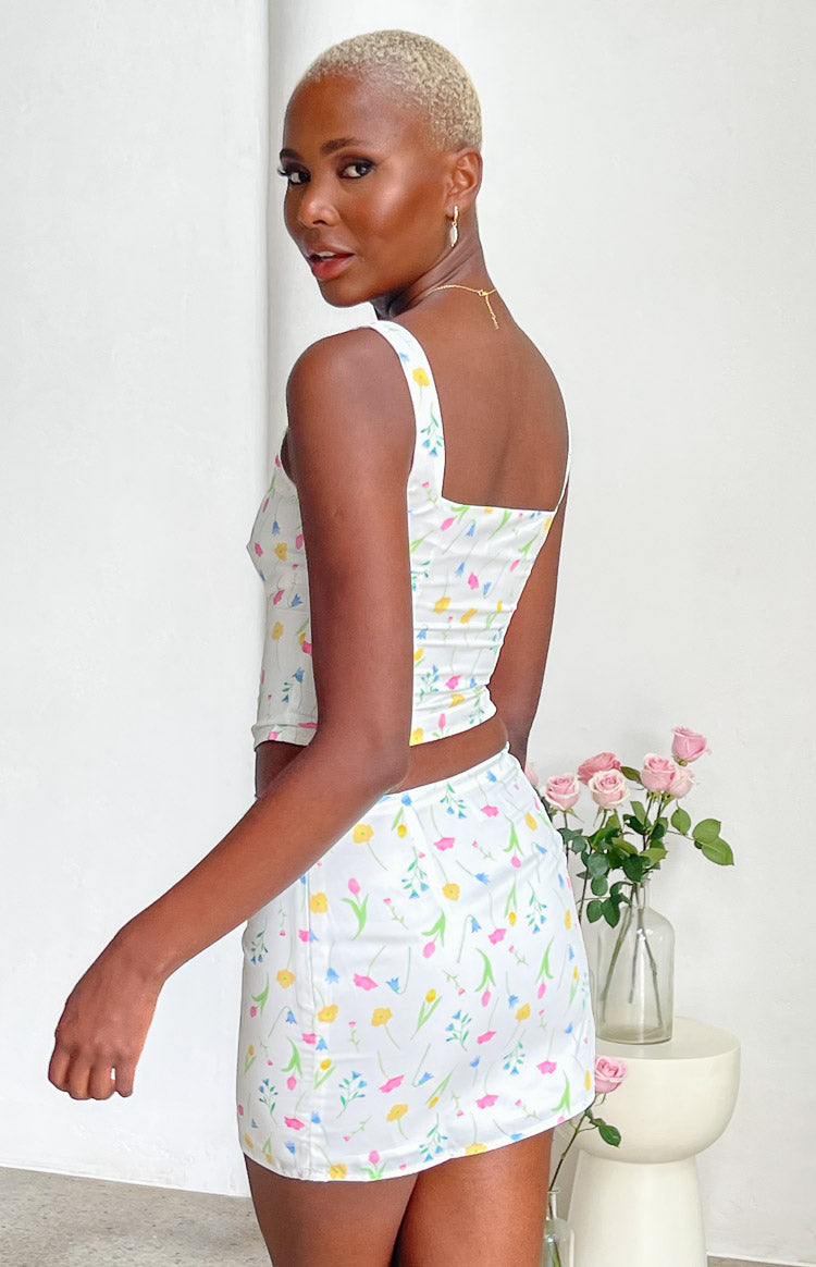Side view of a fitted white mini skirt with a vibrant yellow, pink, and blue floral print