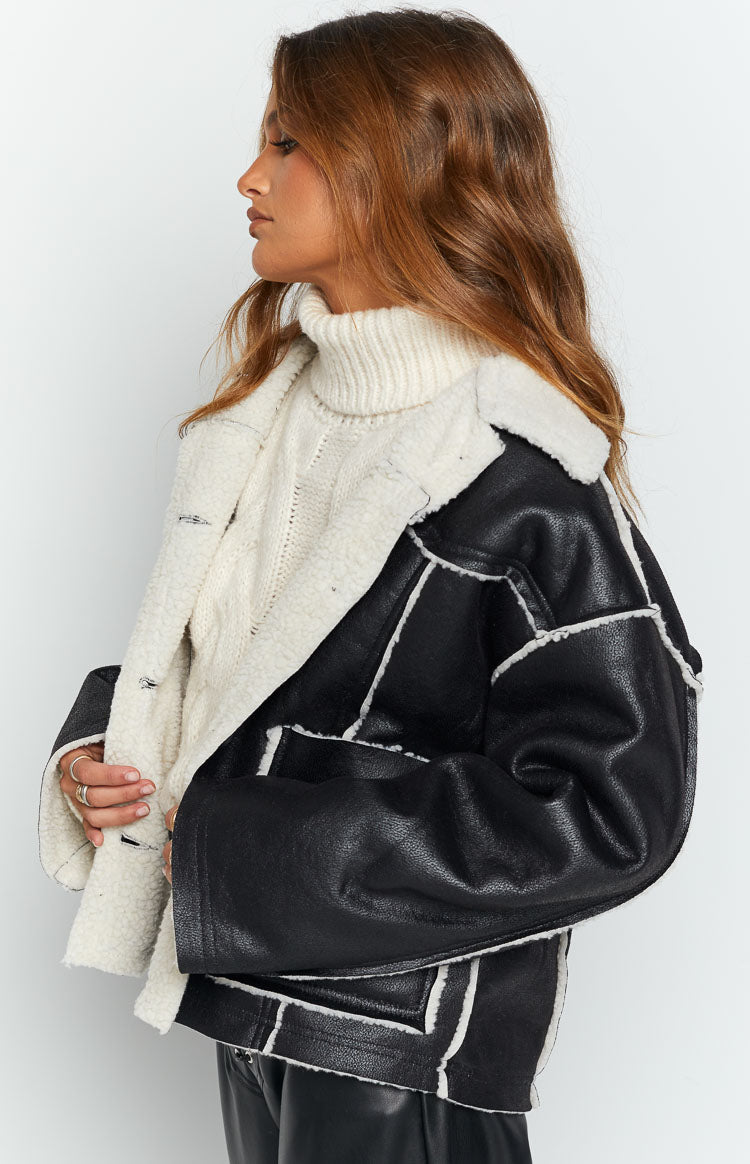 Side view of a black faux leather jacket with white sherpa fleece lining and trim, showing the wide collar