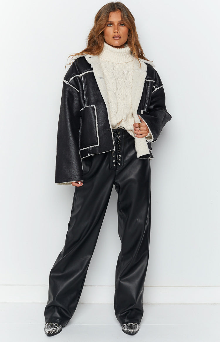 Front view of a black faux leather jacket with white faux fur lining and trim on the lapels and seams