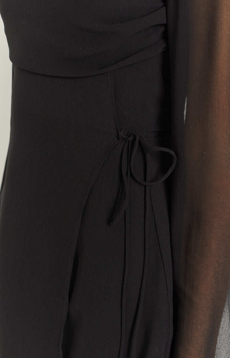 Close-up of the black mini dress side tie detail creating an adjustable slit and subtle ruching