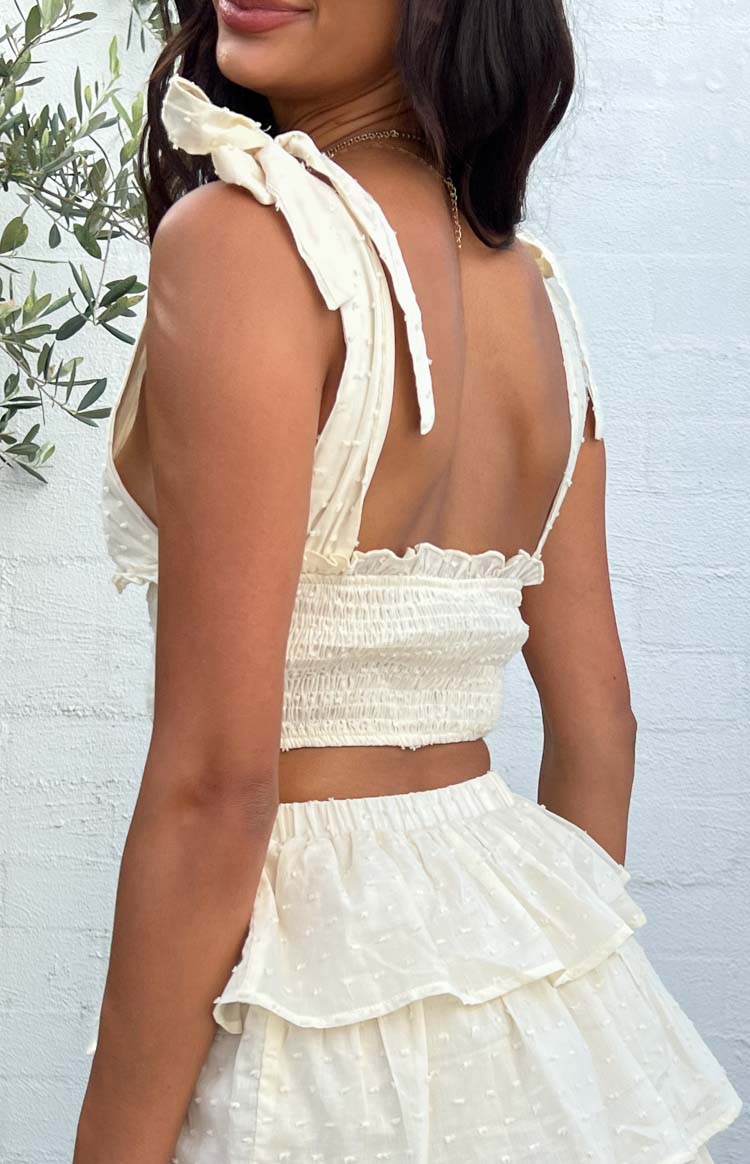 Rear side view of cream shoulder tie top showing tied shoulder straps, shirred back, and dotted texture