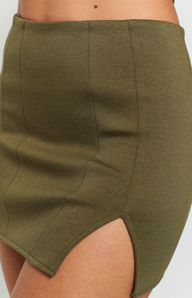 Close-up of the high side slit and the structured vertical panel seams of the khaki mini skirt