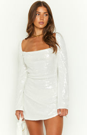 White sequin mini dress featuring a square neckline, long sleeves, and subtle side ruching