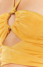 Close-up of the gold ring and ruched detail on the yellow halter top, highlighting the side cut-out