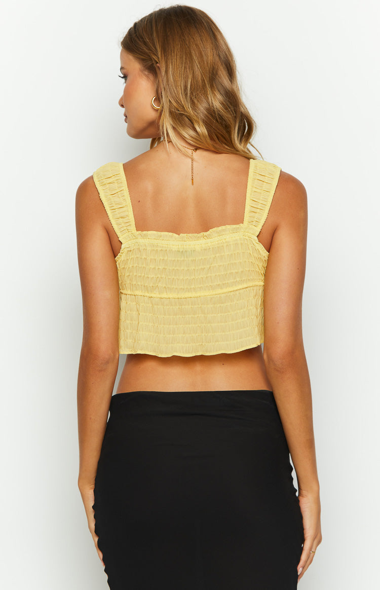 Rear view of a yellow shirred crop top with a square back neckline and wide ruched straps