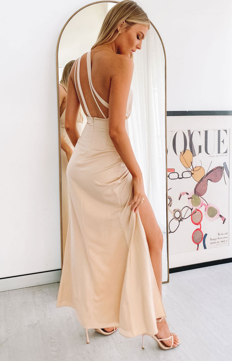 Side view of a gold satin formal dress with a strappy open back and a high side slit
