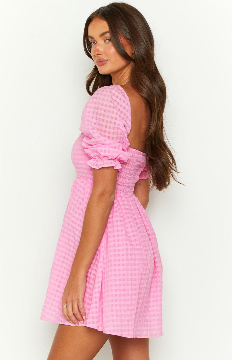 Side view of a pink gingham babydoll mini dress with a square back neckline, shirred panel, and puff sleeves