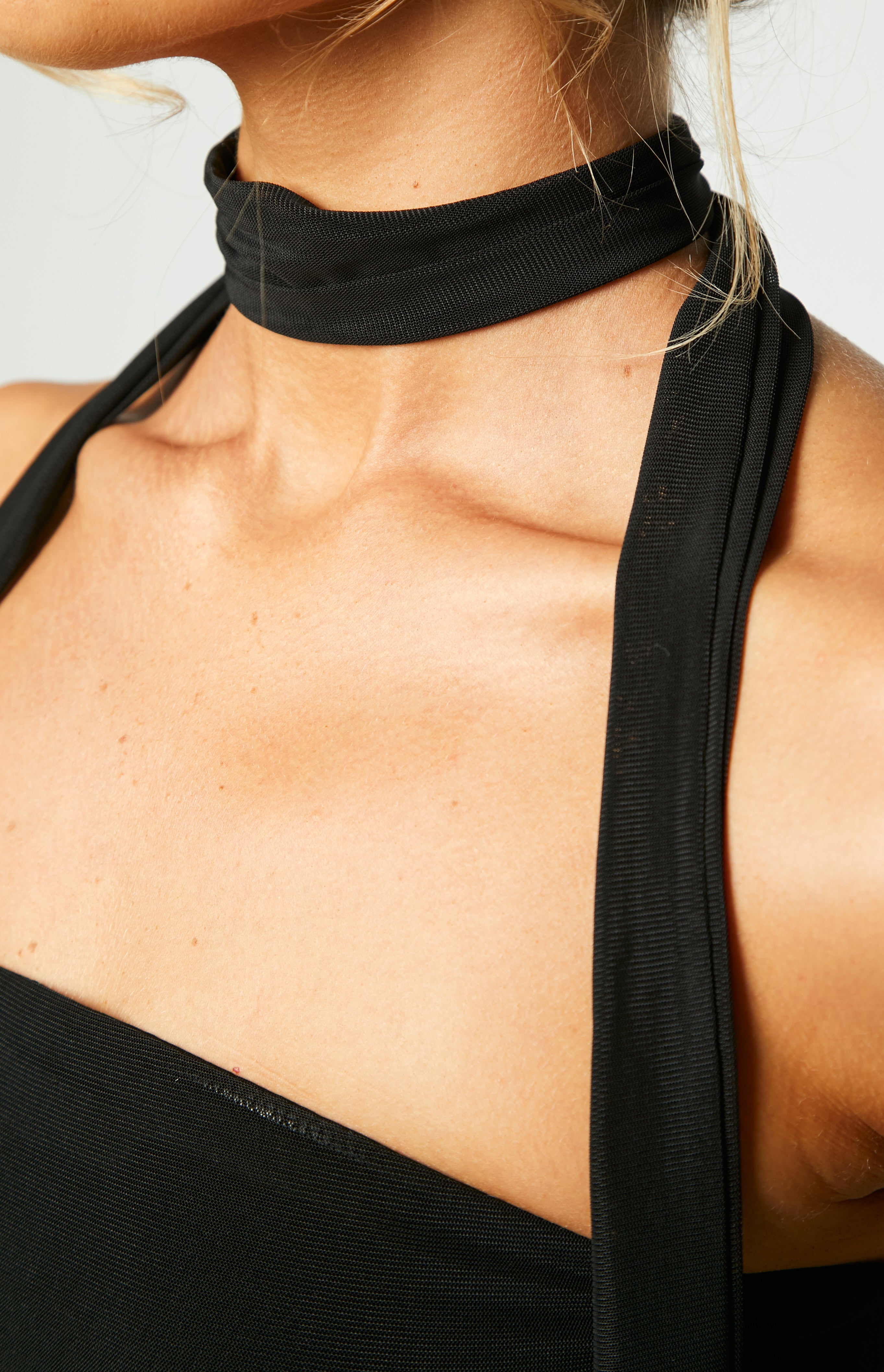 Detail shot of the black mesh scarf tied around the neck and the textured black mesh fabric of the dress