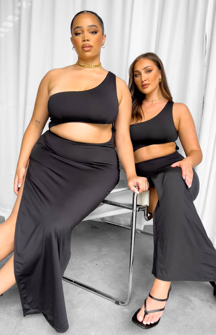 Full length view of the black one-shoulder maxi dress with a wide midriff cutout and high side split