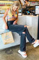 Distressed black wash wide leg jeans with large rips on the knees and thighs
