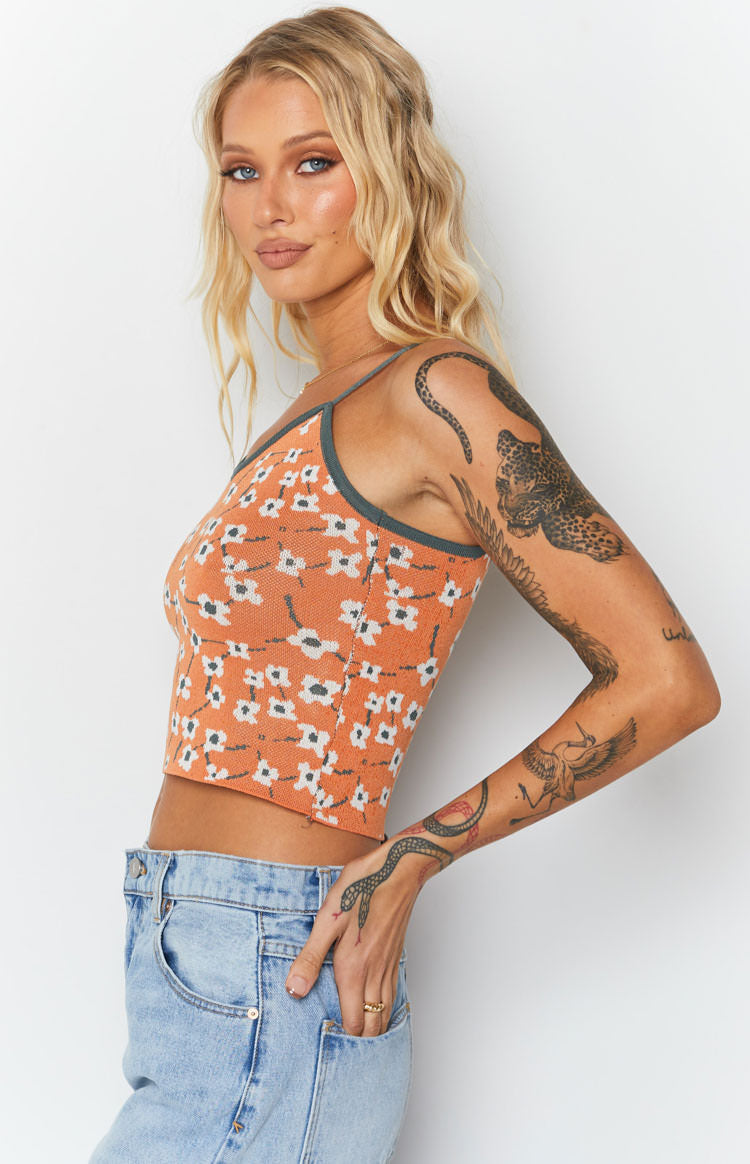 Orange knit crop top with white blossom pattern, scoop neckline, thin spaghetti straps, and grey trim