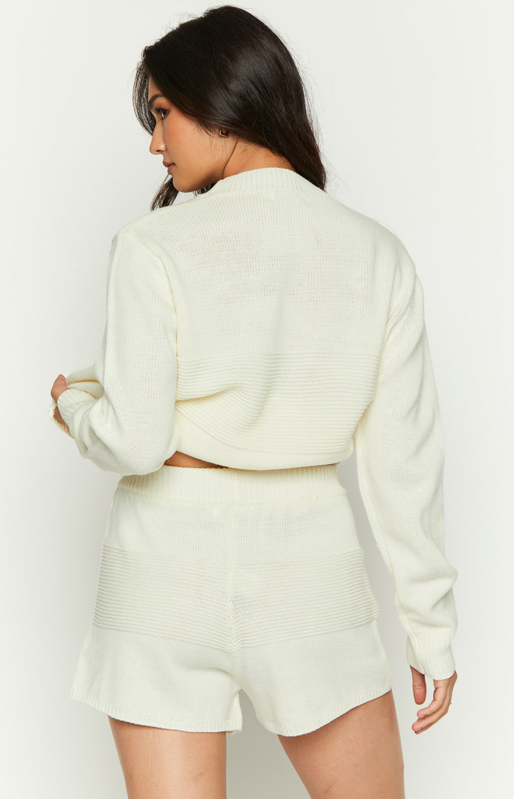 Rear view of a cream long sleeve knit top with a ribbed texture and cropped hem