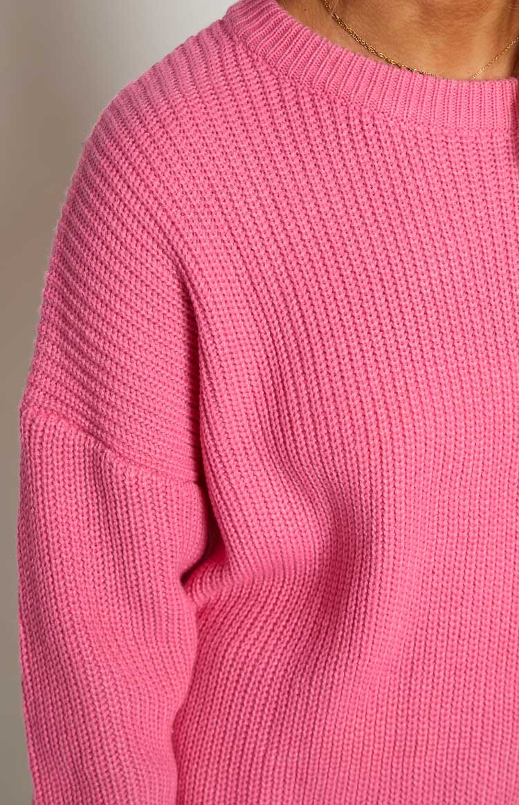 Close-up of the pink ribbed knit fabric, showing the crew neck, shoulder, and sleeve texture of the sweater dress