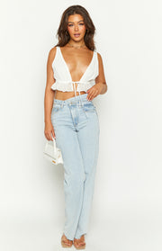White sleeveless crop top with a deep V-neckline, tie-front closure, and a ruffled hem