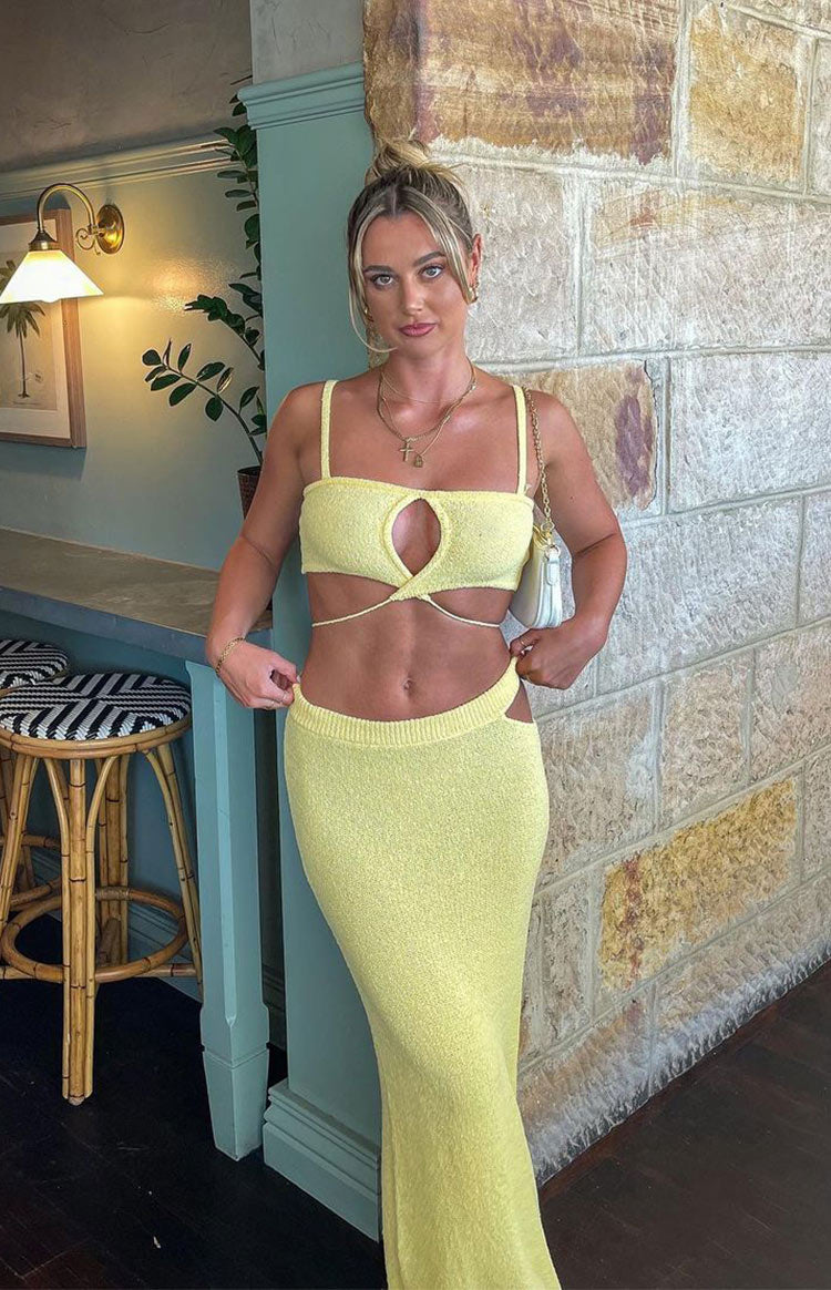 Yellow knit crop top featuring a front oval cutout, thin shoulder straps, and long crisscross waist straps